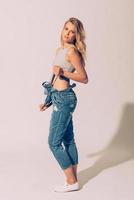 Denim beauty. Full length studio shot of beautiful young woman stretching her jeans overall and looking at camera photo