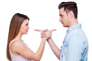 Mutual claims. Side view of beautiful young loving couple pointing each other while standing against white background photo