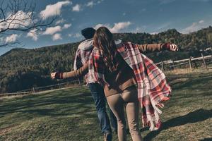 Rear view of young couple spending carefree time while running outdoors photo