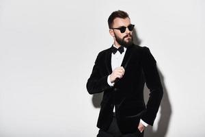 Perfect in every way. Handsome young man in full suit adjusting his jacket and looking away while standing against grey background photo