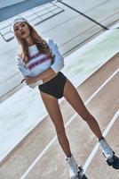 Feeling free to be herself. Full length of attractive young and trendy woman in roller skates standing on stadium outdoors photo