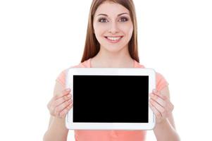 Copy space on her tablet. Attractive young woman showing her digital tablet and smiling while standing isolated on white photo