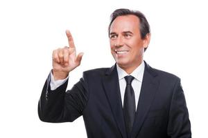 Working on transparent wipe board. Portrait of confident mature man in formalwear touching transparent wipe board with finger while standing isolated on white background photo