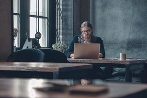 Full concentration at work. Serious young man in smart casual wear working using computer while sitting at the office desk photo