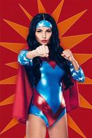 Are you ready to fight Beautiful young woman in superhero costume looking at camera while standing in fighting stance against red background photo