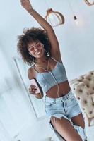 Attractive young African woman listening music while dancing at home photo