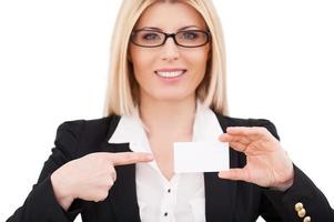 Copy space on her business card. Beautiful mature businesswoman pointing her business card and smiling while standing isolated on white photo