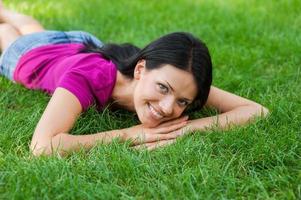 Beauty in nature. Beautiful young woman lying in grass and smiling to you photo