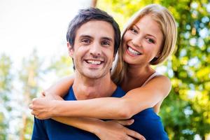 Happy to be together. Low angle view of beautiful young loving couple standing outdoors together while woman hugging her boyfriend and smiling photo