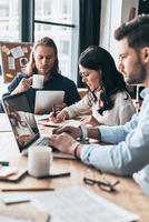 todo el mundo tiene cosas que hacer. jóvenes colegas modernos con ropa informal inteligente que trabajan mientras pasan tiempo en la oficina foto