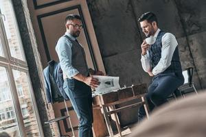 Sharing opinions. Handsome young man choosing design with his client while spending time in the workshop photo