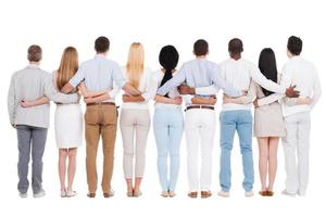 United team. Full length rear view of group of diverse people bonding to each other while standing against white background photo