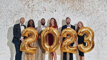 grupo de personas hermosas en ropa formal que llevan números de color dorado y sonríen foto