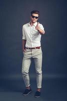 Maybe you Full length of confident young handsome man in sunglasses pointing you and looking at camera while standing against grey background photo