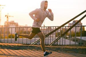 Moving to his goal. Side view of confident young man running along the bridge photo