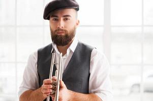 Ready for improvising. Handsome young bearded men standing with trumpet in his hands photo