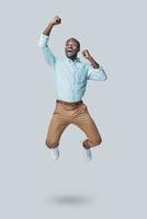 un joven africano juguetón gesticulando y gritando mientras flotaba sobre un fondo gris foto