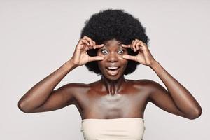 Portrait of beautiful young African woman touching face and looking surprised photo