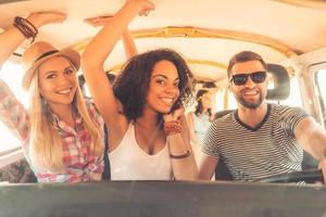 Enjoying great roadtrip with friends. Group of cheerful young people having fun while sitting inside of minivan photo