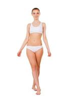 Young and healthy. Full length of attractive young woman in white bra and panties standing isolated on white photo