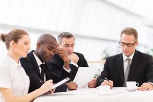 Tired business people. Four business people in formalwear looking tired while sitting together at the table photo