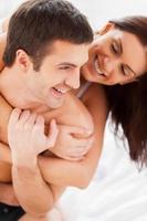 Happy to be together. Beautiful young loving couple having fun while sitting together in bed photo