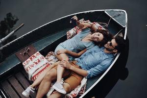 Young and free. Top view of beautiful young couple taking selfie using smart phone while lying in the boat photo