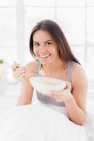 Having a breakfast in bed. Cheerful young smiling woman having a breakfast in bed and smiling at camera photo