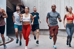 Group of young people in sports clothing jogging while exercising outdoors photo