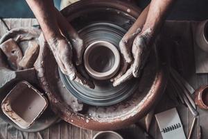 Making it together. Top view of potter teaching child to make ceramic pot on the pottery wheel photo