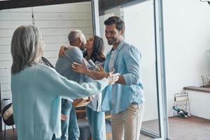 padres mayores sonrientes que se encuentran con una pareja joven dentro de la casa foto