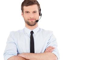 operador masculino. un joven apuesto con ropa formal y auriculares mirando a la cámara y sonriendo mientras se encuentra aislado de fondo blanco foto