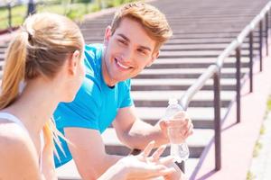 pareja de fitness. pareja joven en ropa deportiva de pie cara a cara y sonriendo foto