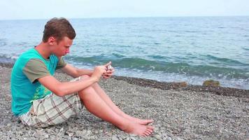 niño jugando en el teléfono inteligente de la orilla del mar video