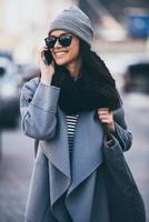 See you soon Beautiful young woman in sunglasses talking on mobile phone and looking away with smile while walking outdoors photo