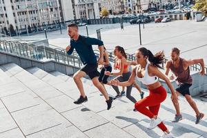 Group of young people in sports clothing jogging while exercising on the stairs outdoors photo