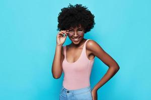 She will melt your heart. Attractive young African woman smiling and looking at camera while standing against blue background photo