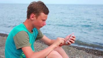 Junge, der auf dem Strand-Smartphone spielt video