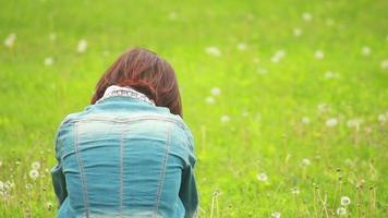 donna seduta su il erba nel il parco indietro per il telecamera video