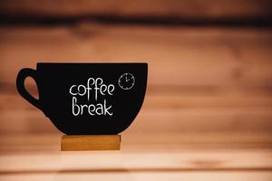 Coffee break. Cup shaped blackboard with hand writing text at wood background photo