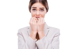 A little bit nervous about this business. Nervous young businesswoman biting her nails while standing against white background photo