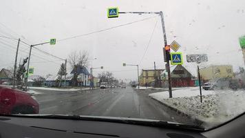 The car is standing at a red traffic light, inside view. View of the city street through the windshield of the car. video