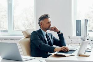 Unrecognizable man in formal business wear using computer while sitting at his working place photo