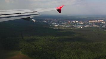 avion approchant de l'atterrissage, pov. vue depuis la fenêtre de l'avion sur la forêt verte et la ville video