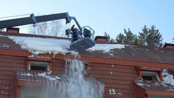 arbetstagare på hiss lastbil avlägsnande snö från de tak av de byggnad, långsam rörelse video