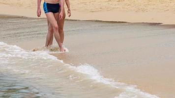 coppia a piedi a piedi nudi su bagnato sabbia nai Harn spiaggia, Phuket video