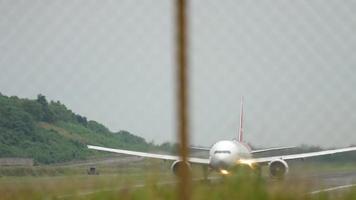 Front view through airport fence of widebody passenger plane taking off. Tourism and travel concept video