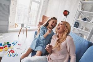 alegría sincera. vista superior de madre e hija riendo mientras pintan en casa foto