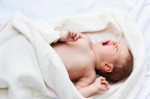 Little baby crying. Top view of little baby lying in bed and crying photo