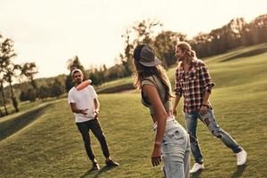 grupo de jóvenes con ropa informal tirando discos de plástico mientras pasan tiempo sin preocupaciones al aire libre foto